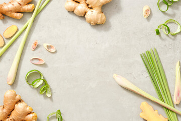 Frame with fresh lemongrass, ginger root and lemon peel on gray background. Space for text and...