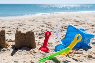 Sand castle at the beach with sand toys. Ocean in the background. Copy space. Holiday, vacations background.