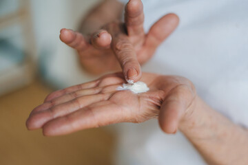Close-up portrait hands of elderly woman applying cosmetic cream. The concept of loving skin cream.
