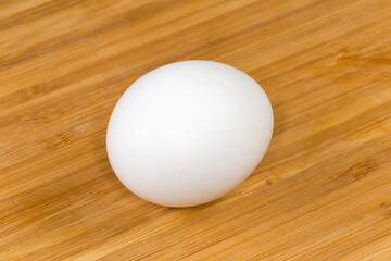 Whole white chicken egg, top view on a wooden surface