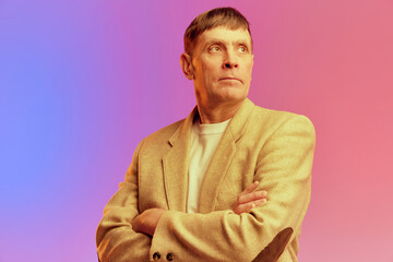 Portrait of mature, middle-aged man in jacket posing with serious face over gradient pink purple...