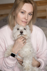 Close up portrait of blond woman hugging little white lap dog