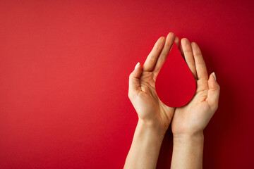 World donor day concept with hand holding paper red drop on white background - obrazy, fototapety, plakaty