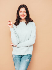 Young beautiful smiling female in trendy summer jeans and sweater clothes. Sexy carefree woman posing near beige wall in studio. Positive model isolated. Cheerful and happy