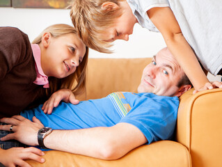 Family Life, Demanding Children. A wry smile from a father distracted by his cheeky persistent...