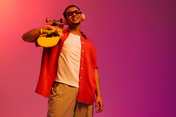 African guy posing with skateboard isolated over gradient neon background