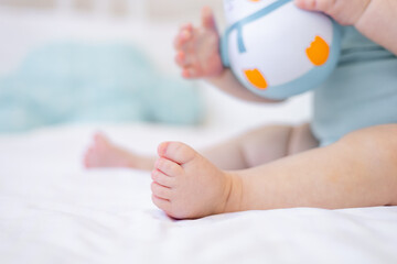 the legs of a small child close-up on a white cotton bed, the foot of a baby