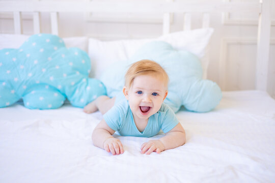 Smiling Or Laughing Baby Boy On The Bed At Home In Blue Clothes Woke Up In The Morning Or Goes To Bed, Happy Childhood And Family