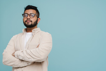 Indian man standing with arms folded isolated over blue background