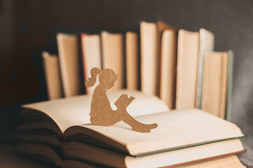A little girl reads a dream book on the background of old books