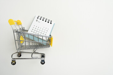 Shopping cart toy and calendar from the supermarket on table with white background, Sale buy mall...