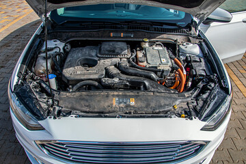 Engine and motor system under the open hood of a white car