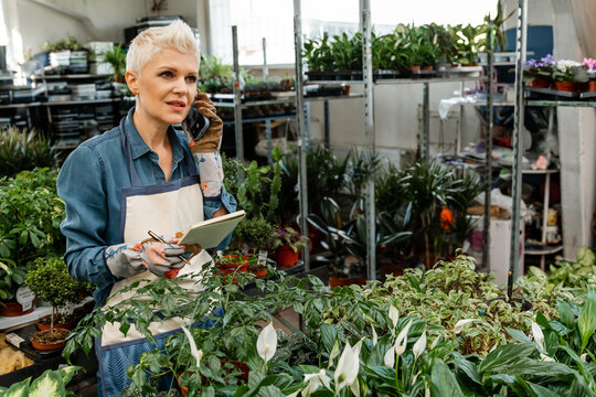 Smiling woman gardener writing orders at her workshop.