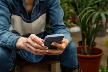 Florist takes an order on the phone at flower shop. Happy mature woman