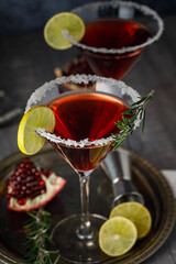 Pomegranate martini cocktail garnished with lemon and rosmarine. Martini alcoholic cocktail or non-alcoholic mocktail. Martinis.