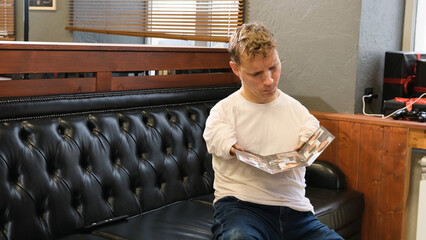 a young man with disabilities is looking at a catalog when choosing a hairstyle in a barber shop