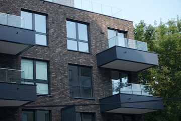 Modern residential building with balconies and dark brick facade. Real estate and housing issues concept.