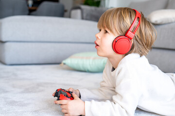 Little boy playing video game console using joystick or controller while sitting at home real people family leisure concept