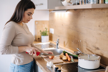 A young beautiful woman is preparing lunch in her kitchen at home. Vegan