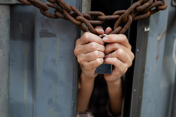  woman trapped in an illegal cargo container locked with chains and keys. Has the idea of trying to escape and seeking freedom from the outside : Concept of human trafficking