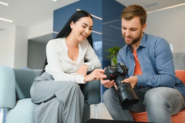Young photographer man in blue shirt watching photo with client woman after photo session and...