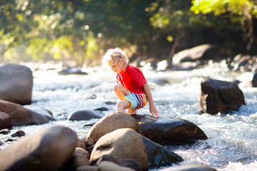 Child hiking in mountains. Kids at river shore.