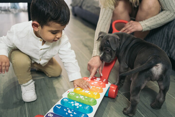 Little autistic boy kneeling down playing and playing with his car with colorful musical keys while his dog watches him.
