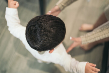 Fototapeta premium Above image of a young autistic child reaching out to be hugged and held by his mother.