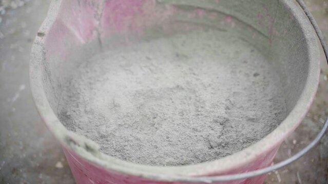 Dry cement in a bucket close-up. Dust in the air from freshly poured into a bucket of cement composition powder, smooth camera movement