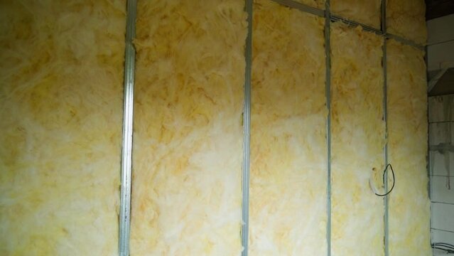 Glass wool insulation and soundproofing. The frame from the U profile along the interior wall is filled with universal insulation, close-up. Smooth camera movement