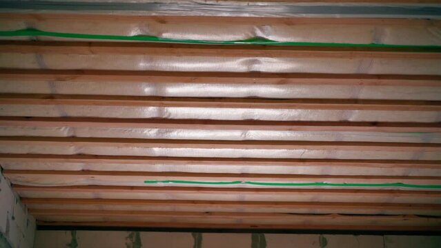 The roof of a private house is insulated from the inside and sheathed with a vapor barrier. The ceiling of the house is ready for interior cladding work. Smooth camera movement 