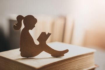 Silhouette of a teenager girl reading a book among the bookshelves