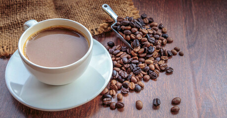 cup of coffee and coffee beans in a sack on  Brown background, top view