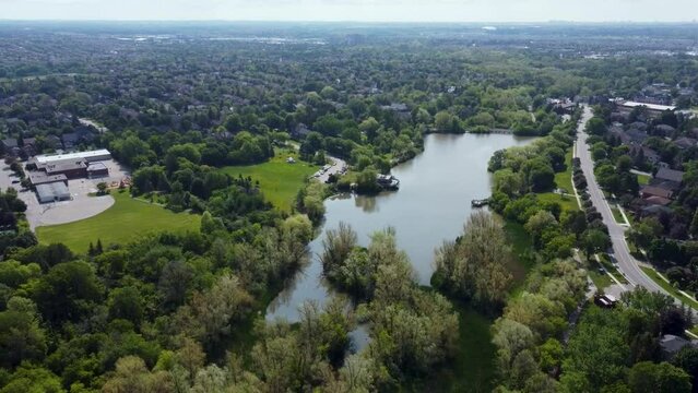 Drone flying over Markham park with a pond on it on a summer day.