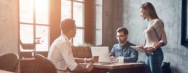 Group of young people having business meeting while working in office together