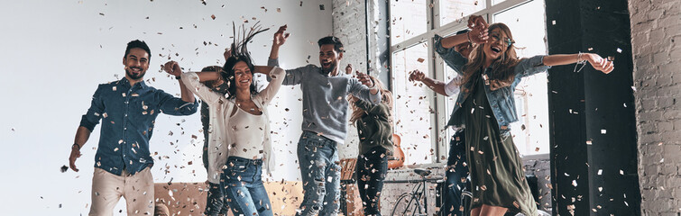Happy young people dancing while spending time together with confetti flying around