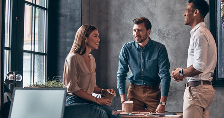 Group of happy young people discussing business while working in office together