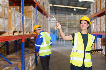 Happy cheerful caucasian white female warehouse worker checking or inspecting a stock inventory in warehouse. Professional occupation in logistic industrial concept.