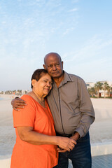 Senior couple standing at the beach together hugging