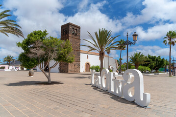 Plaza del pueblo de La Oliva en Fuerteventura rodeada de grandes palmeras y junto a una pequeña...