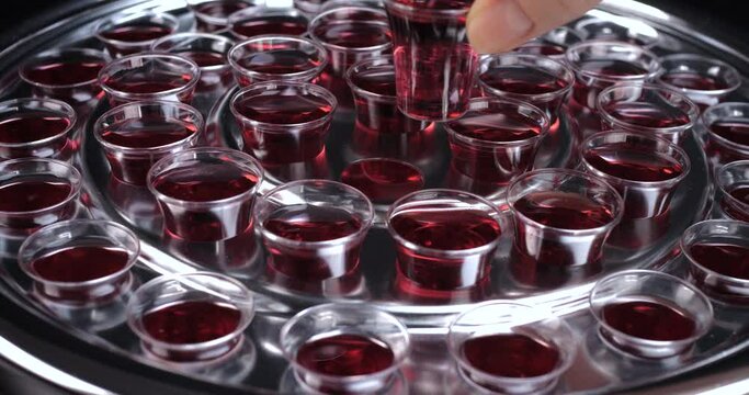 Closeup of young woman taking communion the wine symbol of Jesus Christ blood in small cups on black background. Easter Passover and Lord Supper concept. Dolly shot 4k