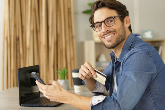 man paying with credit card at home office
