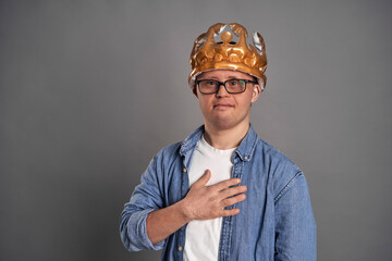 Caucasian man with down syndrome wearing crown on gray background