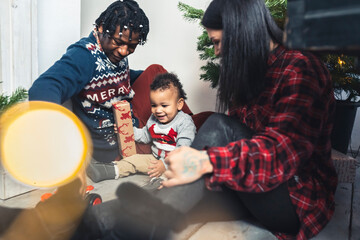 Afro-American man and Caucasian woman opening Christmas gifts with their little son. High quality photo