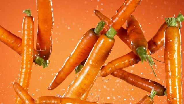 Super slow motion of fresh carrots with water splashes flying in the air. Filmed on high speed cinema camera, 1000 fps.