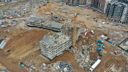 Bird's eye view of a construction site in spring (autumn) of a multi-storey residential complex for the sale of apartments. Construction of the concrete frame of the building. Construction equipment.