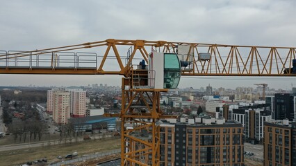 The cab (booth) of the crane operator and the boom of the tower crane close from a height, taken...