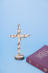 Obraz premium Cross decorated flowers with Holy Bible on blue background. Easter holiday minimalistic concept