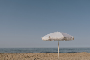 Minimal summer holidays vacation concept. Beach umbrella on beach sand in front of blue sky and...