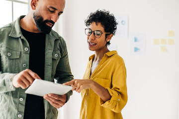 Two business people use a tablet together while having a discussion